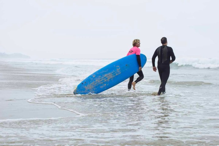 a man in a wet suit carrying a surf board